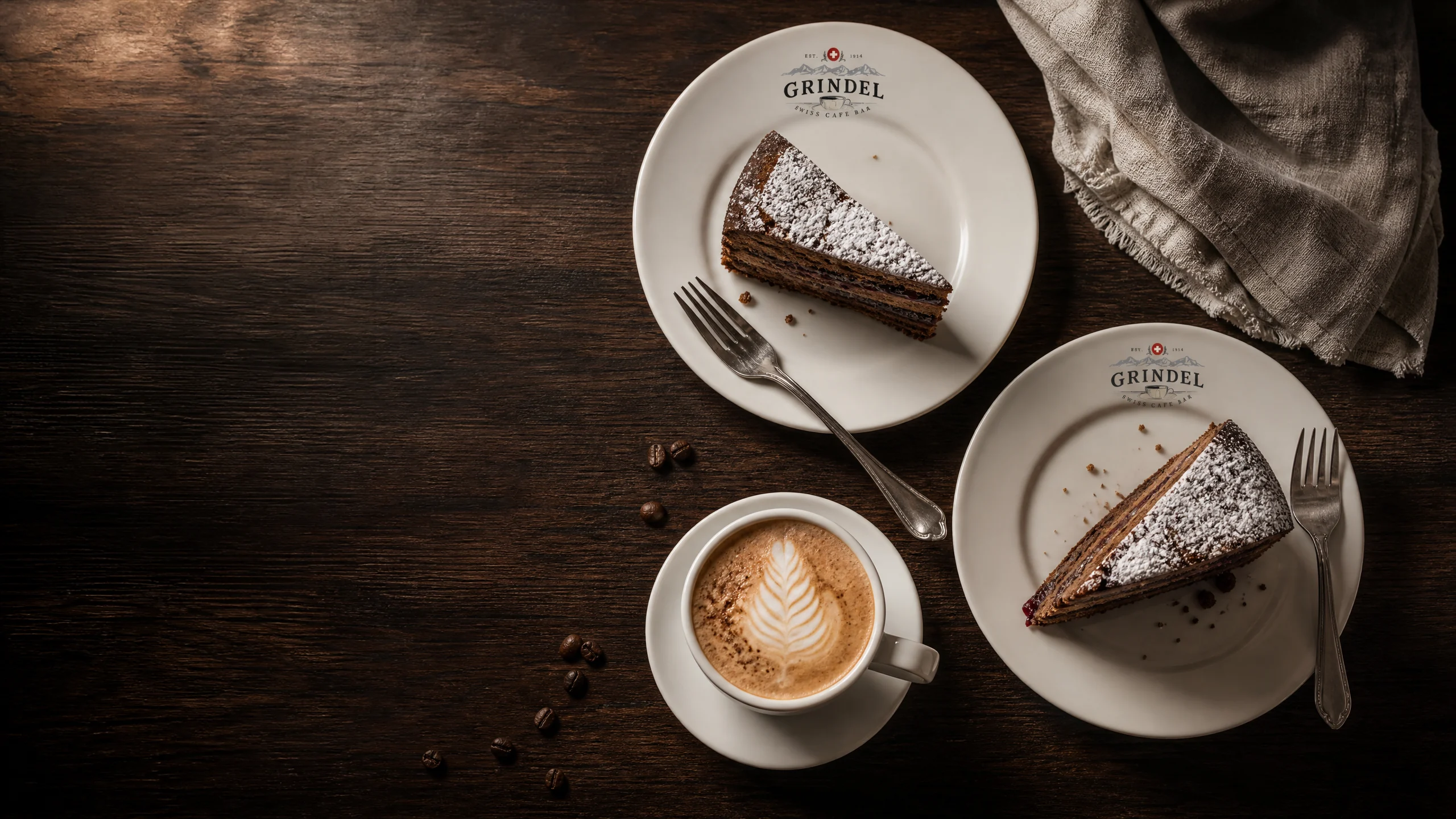 Two slices of Zuger Kirschtorte on Grindel plates beside a cappuccino